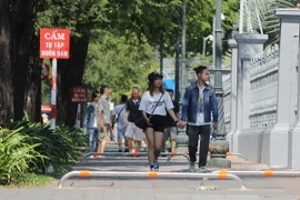 Du khách đi bộ trên vỉa hè vừa lắp các thanh barie tuyến đường Lý Tự Trọng. (Ảnh: Hoàng Hải/TTXVN)