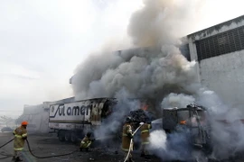 Nhân viên cứu hỏa dập lửa sau khi xe buýt bị đốt phá tại Rio de Janeiro, ngày 2/5. (Ảnh: EPA/TTXVN)