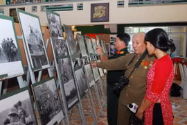 Nghệ sỹ nhiếp ảnh Minh Lộc - giữa - giới thiệu về các tác phẩm của mình tại triển lãm. (Ảnh: Mạnh Linh/TTXVN)