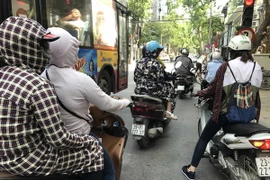 Người dân phải bịt khẩu trang, mũ áo kín mít để tránh nóng khi ra đường. (ẢNh: Minh Quyết/TTXVN)