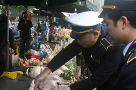 Đóng dấu kiểm dịch vệ sinh an toàn thực phẩm trên gia cầm tại chợ Giếng Vuông, thành phố Lạng Sơn. (Ảnh: Thắng Trung/TTXVN)