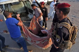 Lực lượng an ninh Iraq chuyển thi thể nạn nhân tại hiện trường vụ tấn công ở Nasriyah ngày 14/9 vừa qua. (Ảnh: AFP/TTXVN)