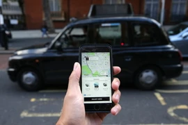 Một khách hàng dùng điện thoại di động để gọi dịch vụ xe của Uber tại London. (Ảnh: AFP/TTXVN )