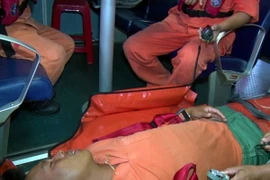 Cán bộ y tế sơ cấp cứu cho anh Cao Minh Tâm trước khi đưa lên bờ để điều trị. (Ảnh: Tá Chuyên/TTXVN)