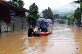 Lực lượng chức năng dùng xuồng đưa người dân vượt qua đoạn ngập sâu tại thị trấn Ít Ong, huyện Mường La. (Ảnh: Nguyễn Cường/TTXVN)