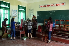 Giáo viên dọn dẹp lại phòng học sau khi nước rút. (Ảnh: Tuấn Anh/TTXVN)