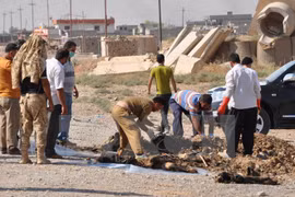 Người dân Iraq đưa xác các nạn nhân lên khỏi một hố chôn tập thể. (Nguồn: AFP/TTXVN)