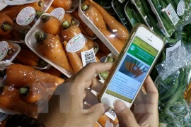 Người dân truy xuất nguồn gốc sản phẩm rau củ trên điện thoại thông minh. (Ảnh: Đỗ Phương Anh/TTXVN) 