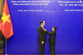 Đồng chí Phankham Viphavan, Ủy viên Bộ Chính trị,Thường trực Ban Bí thư Đảng NDCM Lào, Phó Chủ tịch nước Lào trao tặng Huân chương Vàng Quốc gia của Đảng, Nhà nước Lào cho Chủ tịch nước Trần Đại Quang. (Ảnh: Nhan Sáng/TTXVN)