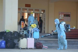 Nhân viên y tế phun thuốc khử trùng vào các vật dụng, hành lý của công dân từ Hàn Quốc trở về. (Ảnh: Văn Dũng/TTXVN)