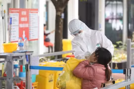 Nhân viên y tế bệnh viện Thanh Nhàn lấy mẫu xét nghiệm COVID-19 cho người đến khám có triệu chứng. (Ảnh: Minh Quyết/TTXVN)