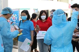 Kiểm tra khai báo y tế, thân nhiệt cho người lao động Dầu khí trước khi bước vào khu vực tiêm chủng. (Ảnh: PV/Vietnam+)