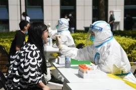 Nhân viên y tế lấy mẫu xét nghiệm COVID-19 cho người dân tại Bắc Kinh, Trung Quốc ngày 26/4. (Ảnh: THX/TTXVN)