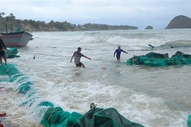 Ngư dân xã An Hòa Hải trục vớt tàu bị sóng đánh chìm lên bờ để sữa chữa. (Ảnh: Xuân Triệu/TTXVN)