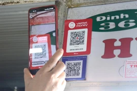 Khách hàng quét mã QR-code khi mua sắm tại chợ Cồn. (Ảnh: Quốc Dũng/TTXVN)