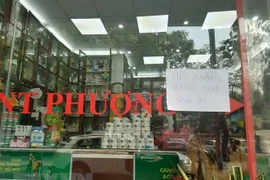 Biển báo hết nước khử khuẩn và khẩu trang y tế được treo trước cửa nhà thuốc Phượng số 19 Quốc Tử Giám. (Ảnh: Tuyết Mai/TTXVN)