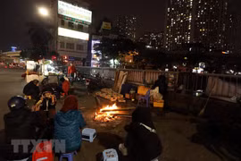 Người Hà Nội sưởi ấm bên đống lửa trên phố trong đêm giá lạnh. (Ảnh: Phan Tuấn Anh/TTXVN)