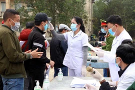 Kiểm tra y tế trước khi người dân hoàn thành cách ly về quê đón Tết. (Ảnh: Công Tường/TTXVN)