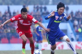 Văn Nam (áo đỏ) trong một pha tranh chấp với Tuấn Anh của Hoàng Anh Gia Lai ở lượt đi V-League 2015. (Ảnh: Minh Chiến/Vietnam+)