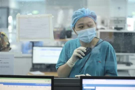 Nhân viên y tế tại khoa điều trị Bệnh viện điều trị bệnh nhân COVID-19 (thuộc Bệnh viện Đại học Y Hà Nội) liên hệ với nhân viên y tế phòng điều hành bằng bộ đàm đảm bảo an toàn, hạn chế sự lây lan của dịch COVID-19. (Ảnh: Minh Quyết/TTXVN)