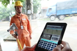 Công nhân Công ty Điện lực Sóc Sơn thuộc Tổng Công ty Điện lực Hà Nội ghi chỉ số côngtơ khách hàng trên địa bàn bằng thiết bị mới. (Ảnh: Ngọc Hà/TTXVN)