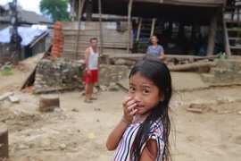 Em Lò Thanh Thảo, học sinh lớp 5 đứng trước ngôi nhà bị nghiêng và có nguy cơ đổ của gia đình mình. (Ảnh: Quyết Đạt/TTXVN)