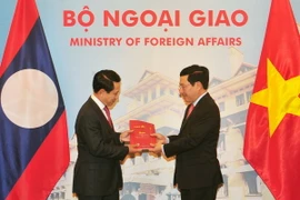 Phó Thủ tướng, Bộ trưởng Ngoại giao Phạm Bình Minh và Bộ trưởng Ngoại giao Lào Saleumxay Kommasith trao đổi tượng trưng hai ấn phẩm văn kiên pháp lý biên giới Việt Nam-Lào. (Ảnh: Nguyễn Khang/TTXVN)