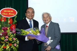 Thủ tướng Nguyễn Xuân Phúc tặng hoa chúc mừng giáo sư Hoàng Tuỵ. (Ảnh: Thống Nhất/TTXVN)