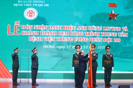 Thủ tướng Nguyễn Xuân Phúc gắn Danh hiệu Anh hùng lực lượng vũ trang Nhân dân thời kỳ kháng chiến chống Pháp lên lá cờ truyền thống của Bệnh viện Trung ương Quân đội 108. (Ảnh: Thống Nhất/TTXVN)