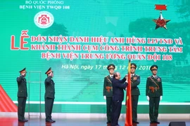 Thủ tướng Nguyễn Xuân Phúc gắn Danh hiệu Anh hùng lực lượng vũ trang Nhân dân thời kỳ kháng chiến chống Pháp lên lá cờ truyền thống của Bệnh viện Trung ương Quân đội 108. (Ảnh: Thống Nhất/TTXVN)