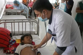 Các bác sỹ tại Bệnh viện Nhi tỉnh Gia Lai thăm khám cho em Đinh Đang bị ngộ độc do ăn thịt cóc. (Ảnh: Dư Toán/TTXVN)