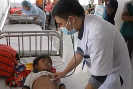 Các bác sỹ tại Bệnh viện Nhi tỉnh Gia Lai thăm khám cho em Đinh Đang bị ngộ độc do ăn thịt cóc. (Ảnh: Dư Toán/TTXVN)