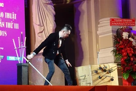 Tiết mục biểu diễn ảo thuật đâm xuyên người nằm trong thùng. (Ảnh: Gia Thuận/TTXVN)