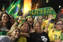 Những người ủng hộ ứng viên đảng Xã hội Tự do (PSL) Jair Bolsonaro vui mừng sau khi kết quả kiểm phiếu sơ bộ được công bố, tại Brasilia ngày 28/10/2018. (Ảnh: AFP/TTXVN)