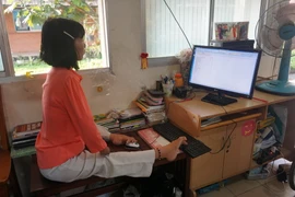 Chị Huỳnh Thị Xậm đang thực hiện công việc ghi chép, nhập dữ liệu tại thư viện của Trung tâm. (Ảnh: Thu Hoài/TTXVN)