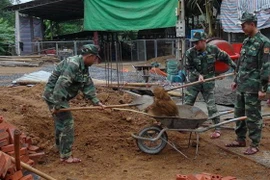Các chiến sỹ Đồn Biên phòng Mường Cai giúp đồng bào vùng biên xây nhà. (Ảnh: Hữu Quyết/TTXVN)