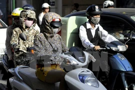 Người dân phải trang bị đầy đủ các trang phục tránh nắng nóng mỗi khi ra đường trong những ngày nắng nóng. (Ảnh: TTXVN)