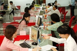 Khách hàng làm thủ tục gửi tiền tiết kiệm tại NHTM cổ phần Kỹ Thương Việt Nam. (Ảnh: Trần Việt/TTXVN)