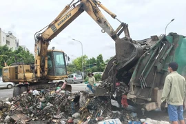 Công nhân vệ sinh môi trường tiến hành dọn dẹp bãi rác tại xã Tân Triều sáng 10/7. (Ảnh: Sơn Bách/Vietnam+) 