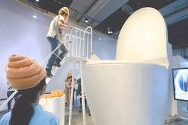 Một phụ nữ phải leo cầu thang để đứng trên chiếc bệ xí khổng lồ trong một cuộc triển lãm tại Bảo Tàng khoa học công nghệ ở Tokyo vào tháng 7/2014. (Nguồn: AFP-JIJI)