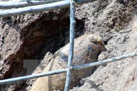 Trái bom dài khoảng 1,3m, đường kính 40- 45cm đã phát lộ khỏi mặt đất. (Ảnh: Chu Quốc Hùng/TTXVN)