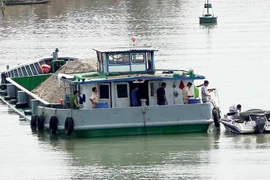 Lực lượng chức năng kiểm tra sà lan chở cát để điều tra nguyên nhân vụ tai nạn. (Ảnh: Công Mạo/TTXVN)