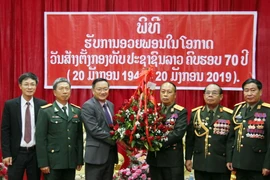 Đại sứ Nguyễn Bá Hùng (trái) trao hoa chúc mừng 70 năm Ngày thành lập Quân đội nhân dân Lào. (Ảnh: Xuân Tú/TTXVN)