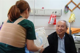 Đại sứ Việt Nam tại Hàn Quốc Nguyễn Vũ Tú (bên phải) tặng quà cho chị L.N.T.G. (Ảnh: Hữu Tuyên/TTXVN)