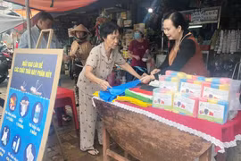 Chị Phan Thị Thúy Phượng (phải) tư vấn cho người tiêu dùng về túi nylon tự hủy sinh học tại chợ Gò Vấp. (Ảnh: Mỹ Phương/TTXVN)
