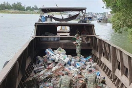 Cán bộ chiến sỹ Đồn Biên phòng Cửa khẩu Long Bình kiểm đếm số phế liệu vừa thu giữ. (Ảnh: Công Mạo/TTXVN)