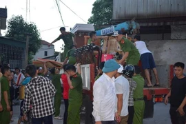 Lực lượng chức năng giúp di dời 80 hộ dân của huyện Nghi Sơn ra khỏi vùng nguy hiểm (Ảnh: TTXVN)
