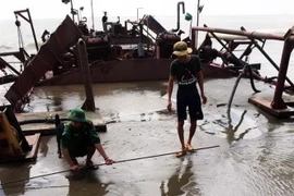 Bộ đội biên phòng Đồn Biên phòng Long Hòa đo kiểm tra lượng cát trái phép trên sà lan 3326 bị thu giữ. (Ảnh: TTXVN)