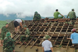 Hơn 250 cán bộ chiến sỹ công an, quân đội có mặt hỗ trợ nhân dân thôn Hoa Tiến (xã Kỳ Hoa, thị xã Kỳ Anh, Hà Tĩnh) lợp lại mái nhà. (Ảnh: Hoàng Ngà/TTXVN)