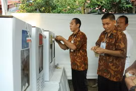 Nhân viên Ủy ban giám sát bầu cử kiểm tra khóa niêm phong hòm phiếu. (Ảnh: Đỗ Quyên/Vietnam+)